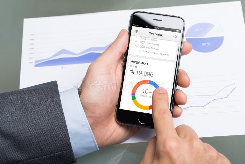 Berlin; Germany - October 10; 2014: Cropped image of businessman using Google analytics on Apple iPhone6 at table. Google analytics is the most widely used website statistics service. Berlin; Germany - October 10; 2014: Cropped image of businessman using Google analytics on Apple iPhone6 at table. Google analytics is the most widely used website statistics service