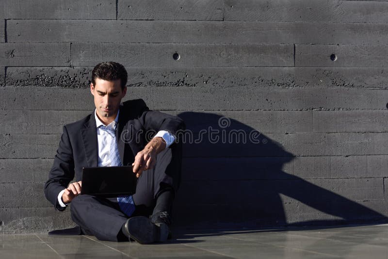 Businessman using a laptop computer sitting in the street