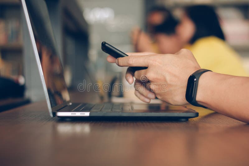 Businessman using laptop and typing on mobile smart phone, business people with technology concept. Close up hand man working. stock image