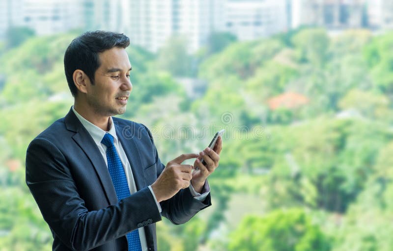 Businessman using mobile phone near office window at office building,communication concept stock image Businessman using mobile phone near office window at office building,communication concept stock image