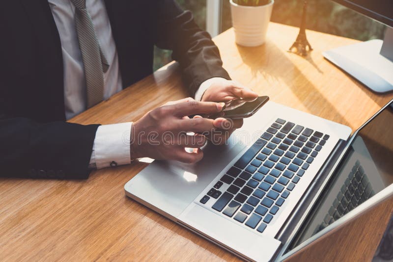 Businessman using smartphone and laptop computer at workplace sitting update or report in email application earnings with network