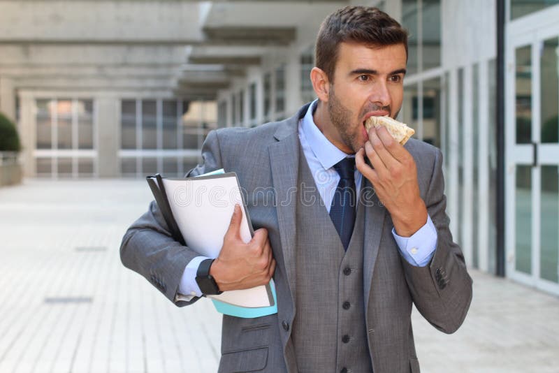 Businessman walking and eating at the same time stock image
