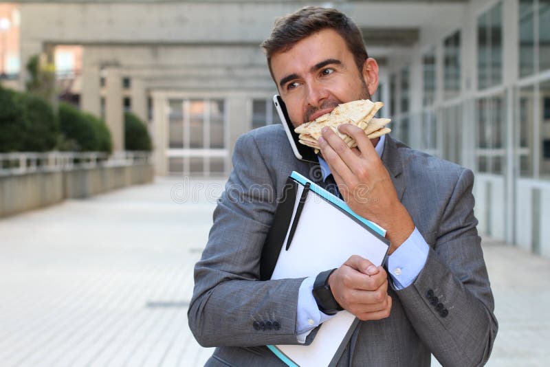 Businessman walking, eating and talking on the phone at the same time royalty free stock images