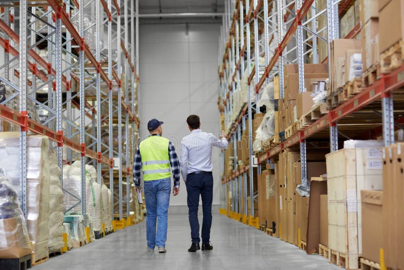 Businessman and worker walking along warehouse stock photo Businessman and worker walking along warehouse stock photo