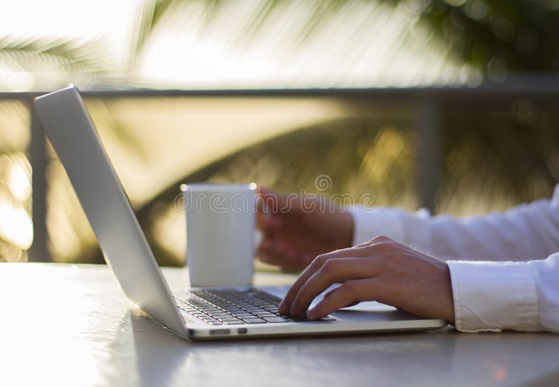 Businessman working with laptop and cup of coffee at sunrise