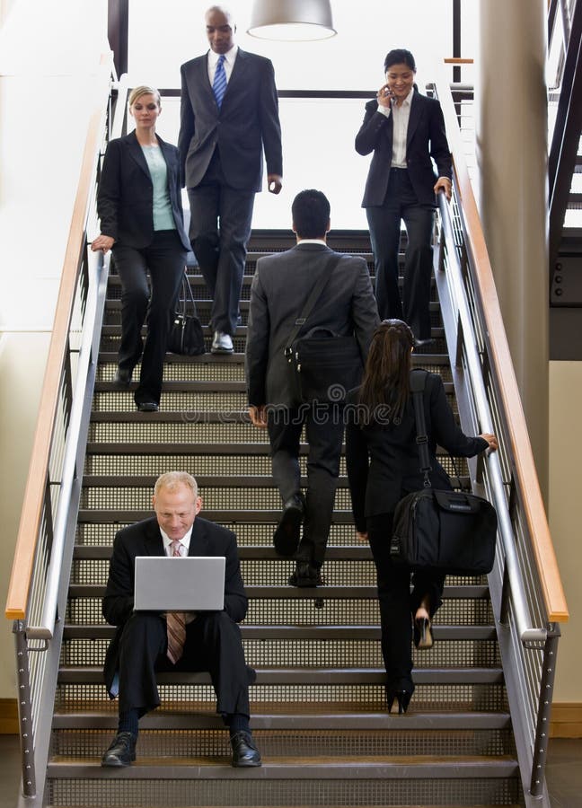 Businessman working on laptop on office stairs