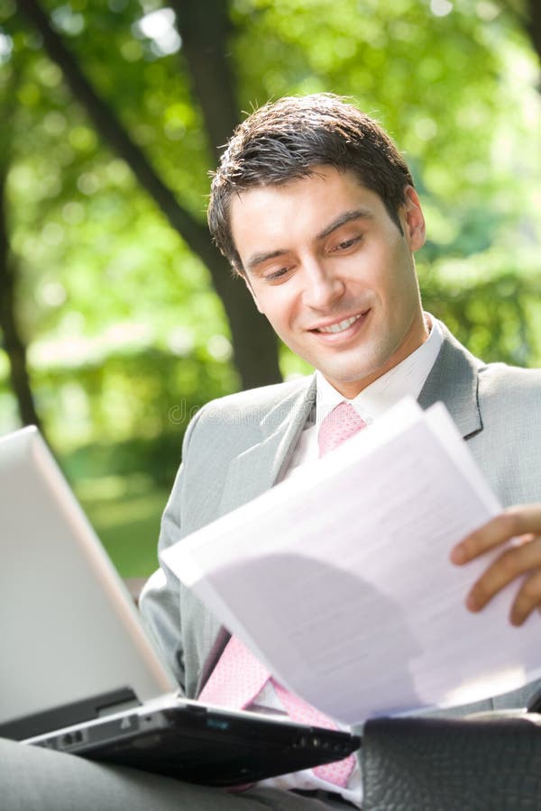 Businessman working with laptop and documents, outdoor. Businessman working with laptop and documents, outdoor