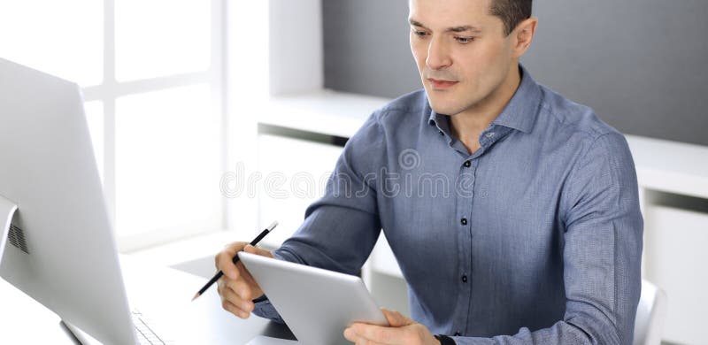 Businessman working with tablet computer in modern office. Headshot of male entrepreneur or company director at royalty free stock image