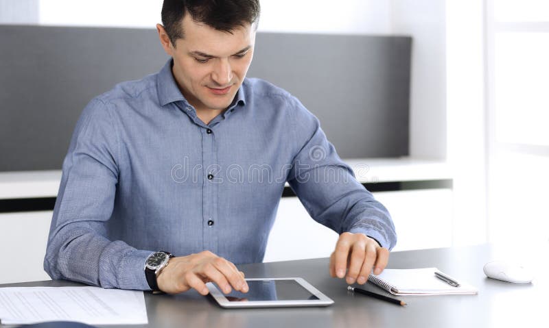 Businessman working with tablet computer in modern office. Headshot of male entrepreneur or company director at stock photography