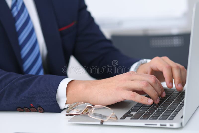 Businessman working by typing on laptop computer. Man`s hands on notebook or business person at workplace. Employment o stock image