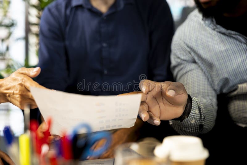 Businessmen in office looking over revenue figures on paperwork, close up stock images