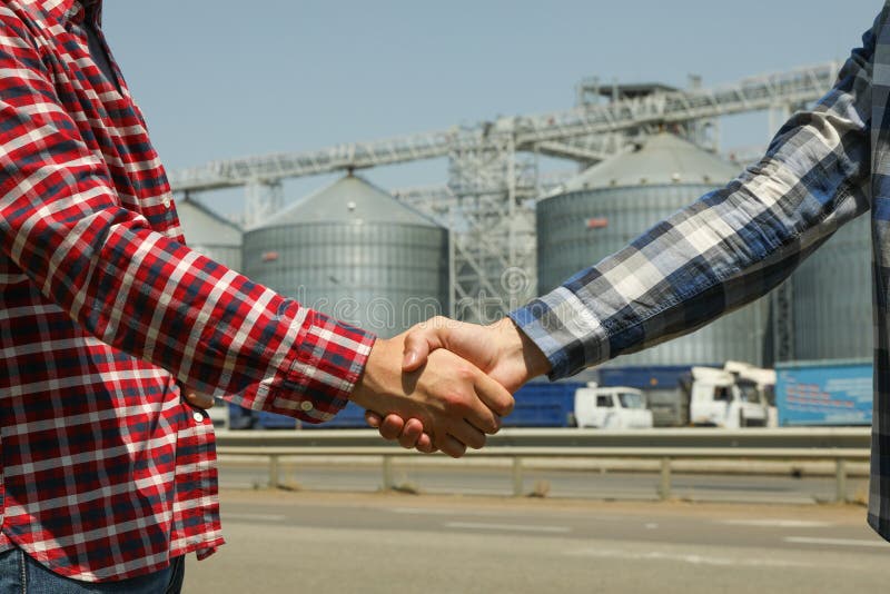 Businessmen shake hands against silos Agriculture business