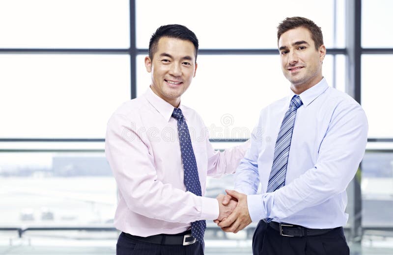 Businessmen shaking hands at airport