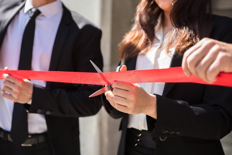 Businesspeople Hand Cutting Red Ribbon