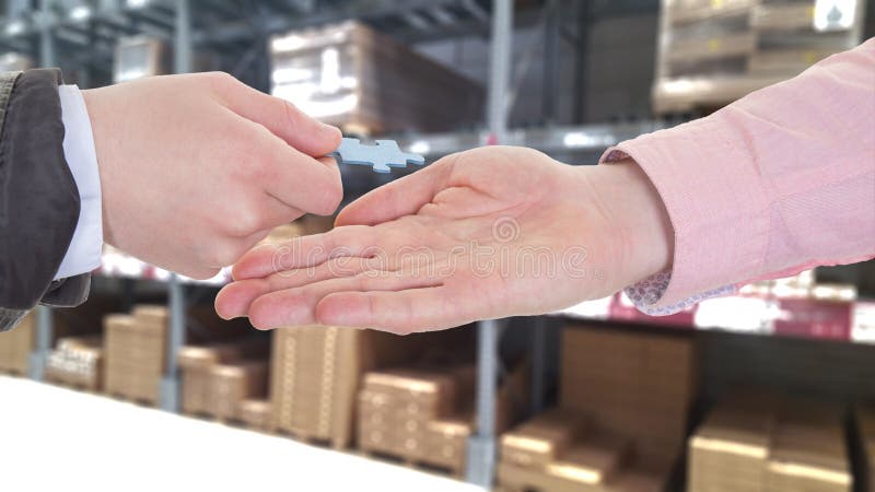 Businesspeople hands exchanging a puzzle piece in a warehouse royalty free stock photography Businesspeople hands exchanging a puzzle piece in a warehouse royalty free stock photography