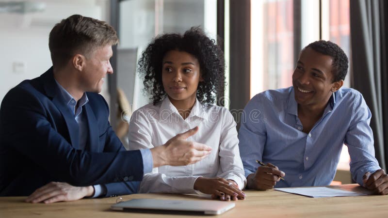 Businesspeople discussing contract conditions before signing at meeting, manager or realtor consulting African American clients in office, successful negotiations concept, hiring process. Businesspeople discussing contract conditions before signing at meeting, manager or realtor consulting African American clients in office, successful negotiations concept, hiring process