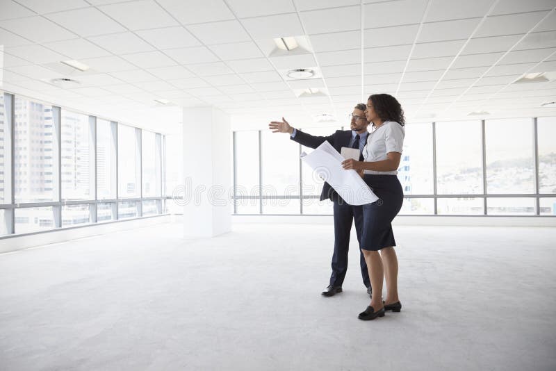 Businesspeople som möter för att se plan i tomt kontor fotografering för bildbyråer Businesspeople som möter för att se plan i tomt kontor fotografering för bildbyråer