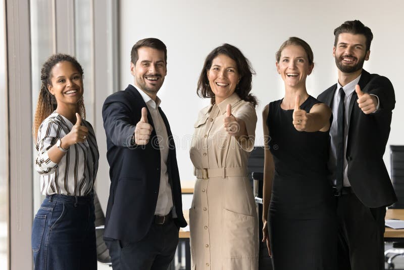 Businesspeople standing together giving thumbs-up gesture to camera royalty free stock images