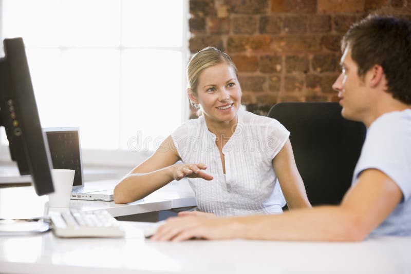 Businesspeople twee in en bureau dat spreekt glimlacht Businesspeople twee in en bureau dat spreekt glimlacht