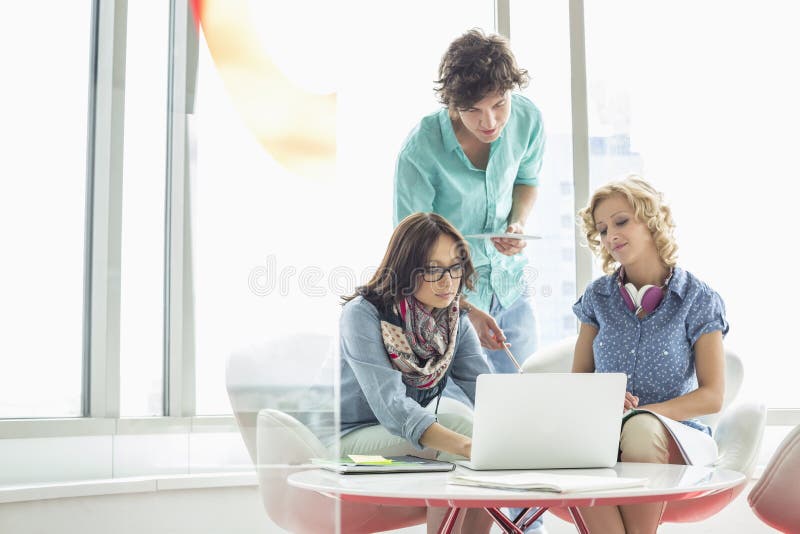 Businesspeople using laptop at table in creative office royalty free stock photos Businesspeople using laptop at table in creative office royalty free stock photos