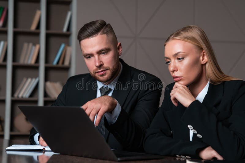 Businesswoman and businessman wearing formal wear sitting working on laptop stock image