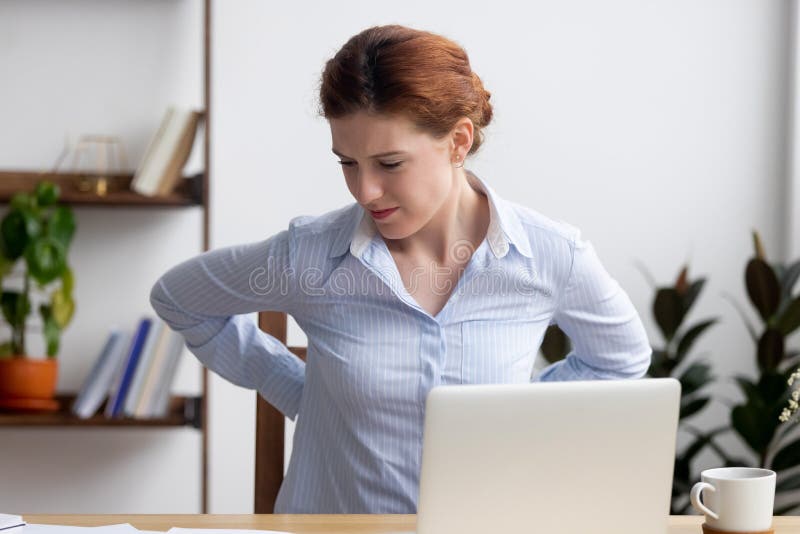 Businesswoman feeling back pain sitting on chair touching aching muscles