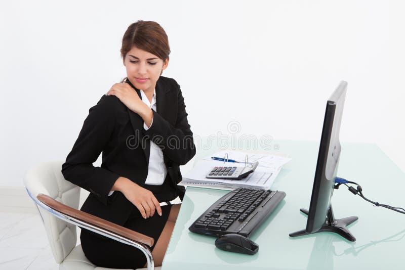Businesswoman having shoulder pain at computer desk stock images Businesswoman having shoulder pain at computer desk stock images