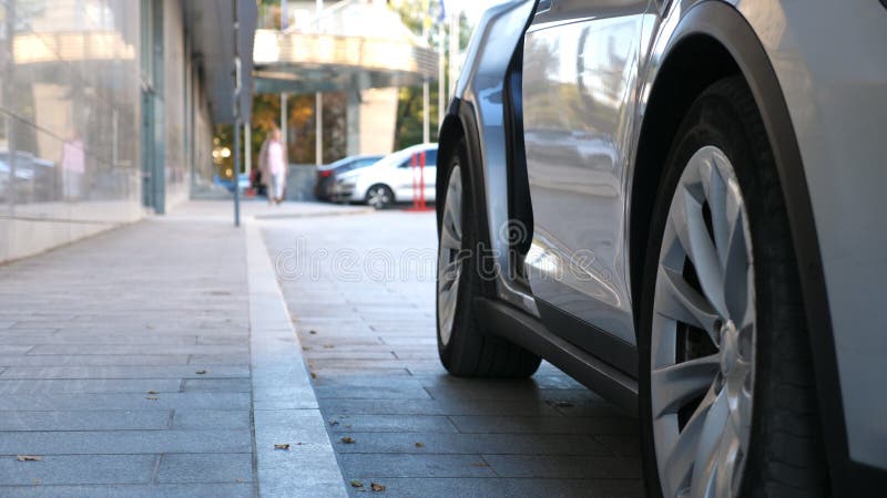 Businesswoman in high heel shoes get in to modern car near office building. Young business woman getting inside to