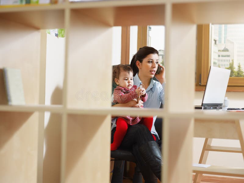 Businesswoman on the phone, holding daughter