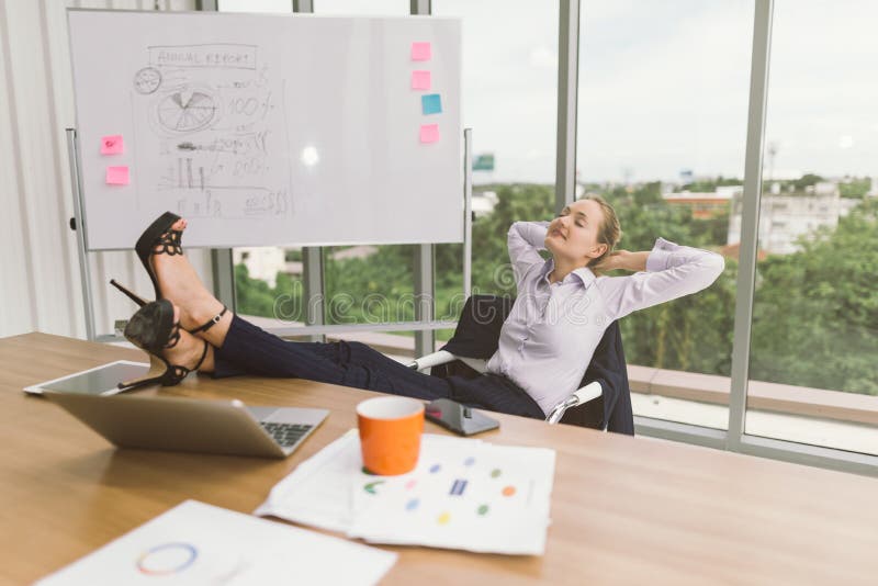 Businesswoman relaxing with feet up at desk in creative office . relax and resting.