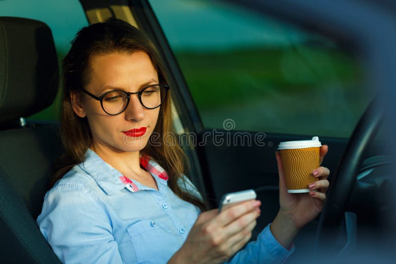 Businesswoman sending a text message and drinking coffee while d