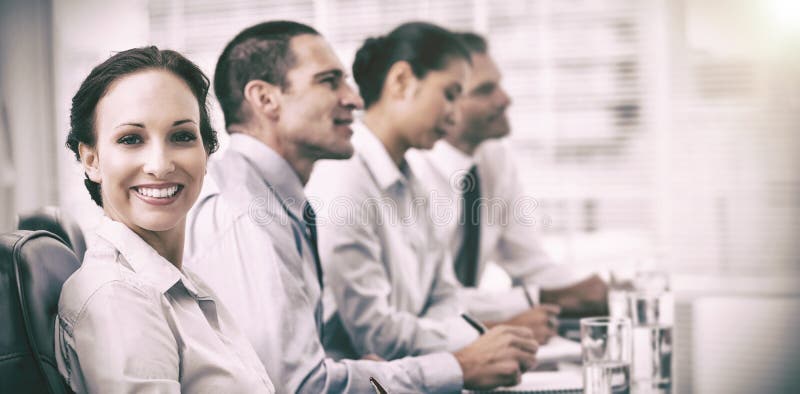 Businesswoman smiling at camera while her colleagues listening to presentation stock photography Businesswoman smiling at camera while her colleagues listening to presentation stock photography