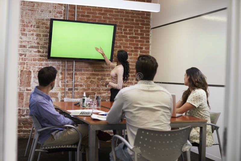 Businesswoman Standing By Screen To Deliver Presentation royalty free stock photo Businesswoman Standing By Screen To Deliver Presentation royalty free stock photo