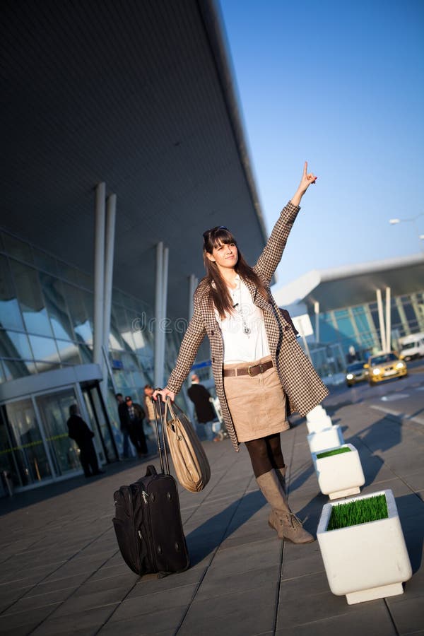 Young business woman who goes from the airport wants to catch a taxi. Young business woman who goes from the airport wants to catch a taxi