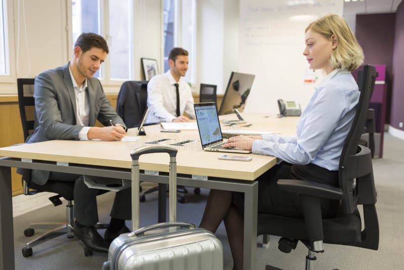Businesswoman in transit with luggage in a coworking office stock photo Businesswoman in transit with luggage in a coworking office stock photo