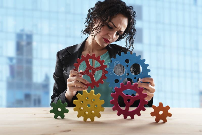 Businesswoman tries to connect gears pieces. Concept of Teamwork, partnership and integration stock images Businesswoman tries to connect gears pieces. Concept of Teamwork, partnership and integration stock images