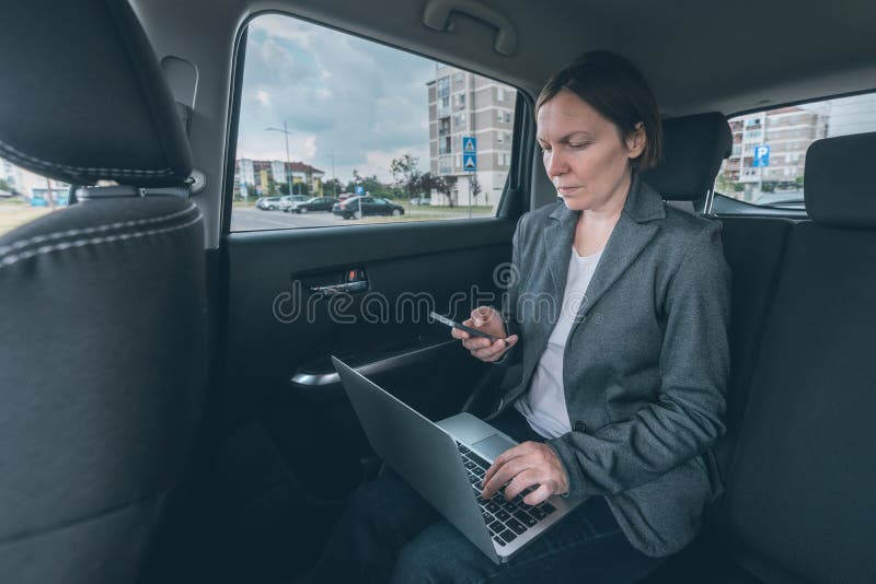 Businesswoman using mobile phone and laptop computer in car stock image Businesswoman using mobile phone and laptop computer in car stock image