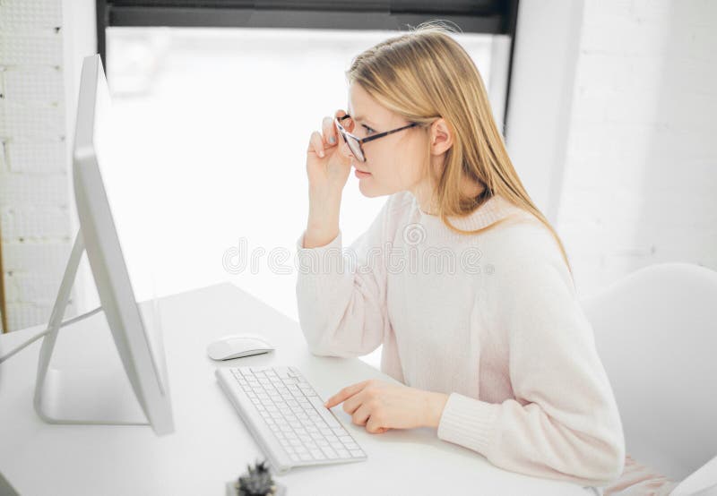 Woman working in office, sitting at desk, using computer and looking on screen stock image Woman working in office, sitting at desk, using computer and looking on screen stock image