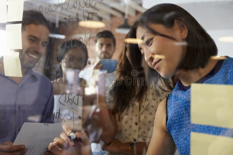 Businesswoman Writing Ideas On Glass Screen During Meeting royalty free stock photo Businesswoman Writing Ideas On Glass Screen During Meeting royalty free stock photo