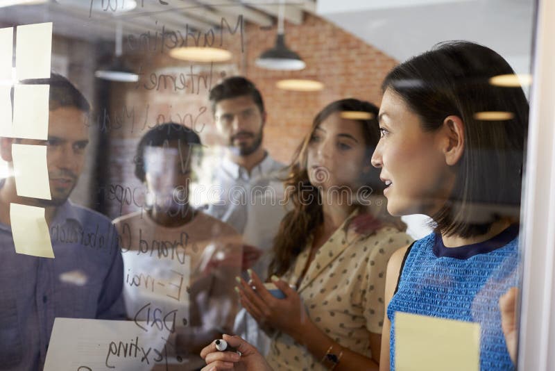 Businesswoman Writing Ideas On Glass Screen During Meeting royalty free stock photography Businesswoman Writing Ideas On Glass Screen During Meeting royalty free stock photography