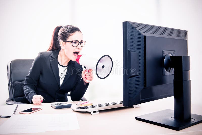Businesswoman yelling through a megaphone sitting in the office royalty free stock photography
