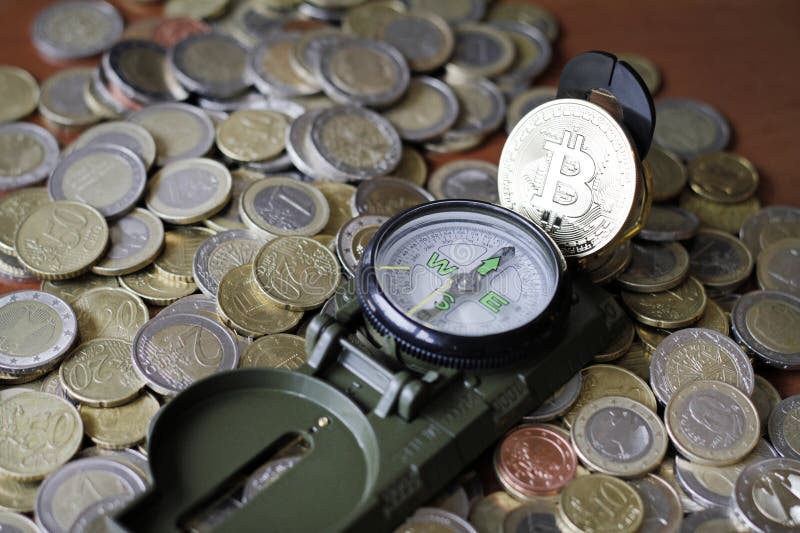 Bussola e bitcoin su una pila di monete in euro immagine stock libera da diritti