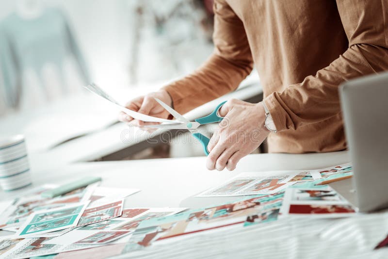 Designer from a fashion studio cutting the pictures for a new catalogue