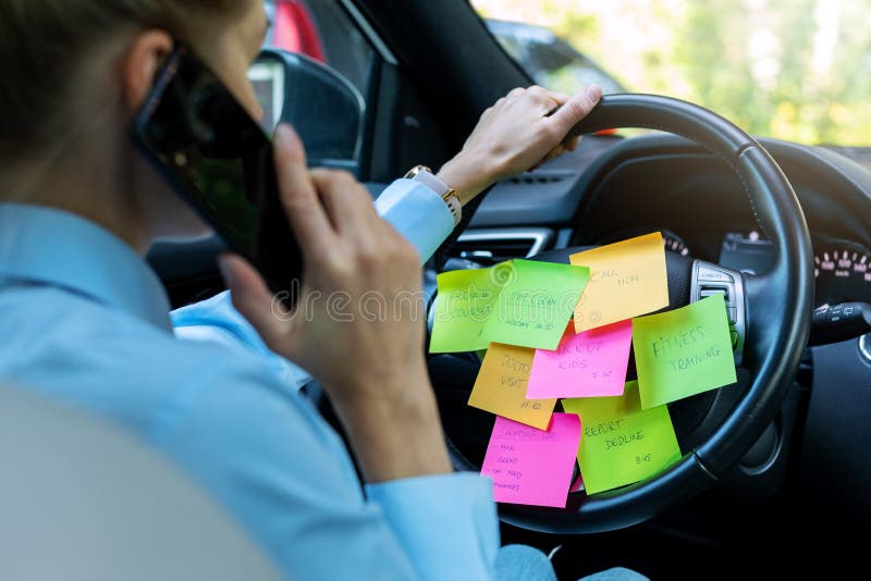 Busy day schedule concept - woman driving car with to do list notes on the wheel