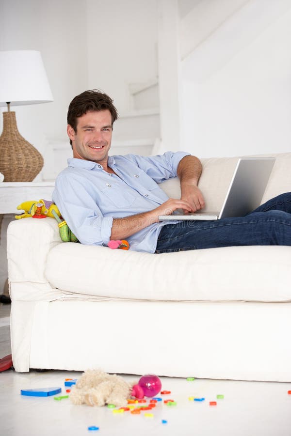 Busy father working at home on laptop royalty free stock photography Busy father working at home on laptop royalty free stock photography
