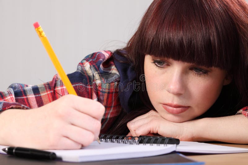 Busy student girl writing homework with pencil