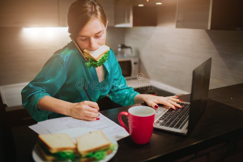 Busy woman eating, drinking coffee, talking on the phone, working on laptop at the same time. Businesswoman doing multiple tasks. Multitasking business person. Freelancer works at night. Busy woman eating, drinking coffee, talking on the phone, working on laptop at the same time. Businesswoman doing multiple tasks. Multitasking business person. Freelancer works at night.