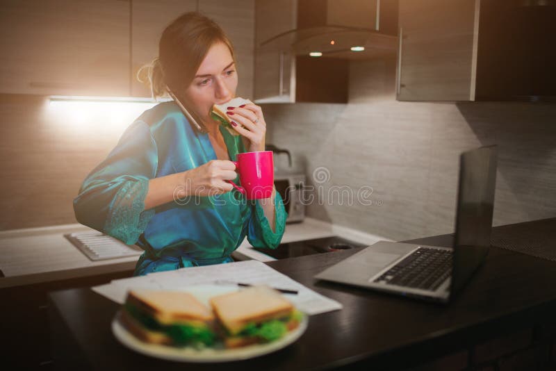 Busy woman eating, drinking coffee, talking on the phone, working on laptop at the same time. Businesswoman doing multiple tasks. Multitasking business person. Freelancer works at night. Busy woman eating, drinking coffee, talking on the phone, working on laptop at the same time. Businesswoman doing multiple tasks. Multitasking business person. Freelancer works at night.