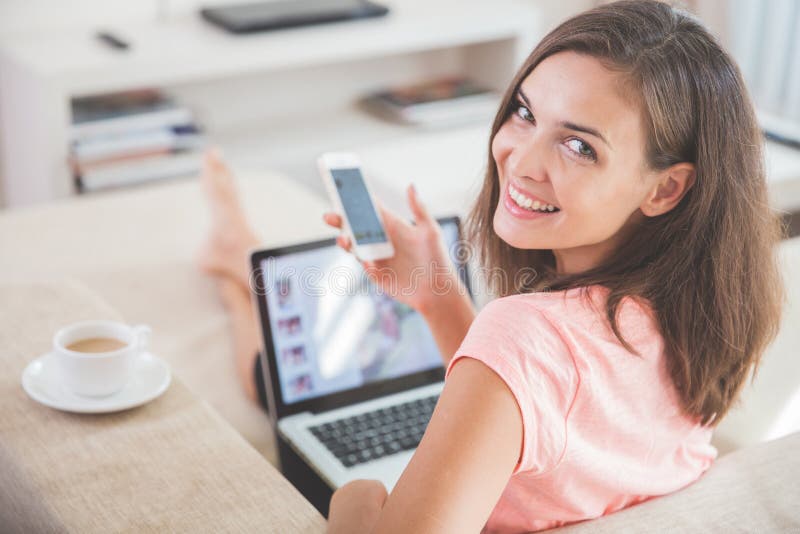 Busy woman at home using mobile phone and laptop at the same tim