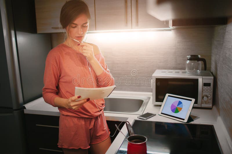 Busy woman preparing coffee, talking on the phone, working on tablet at the same time. Businesswoman doing multiple tasks. Multitasking business person. Freelancer works at night